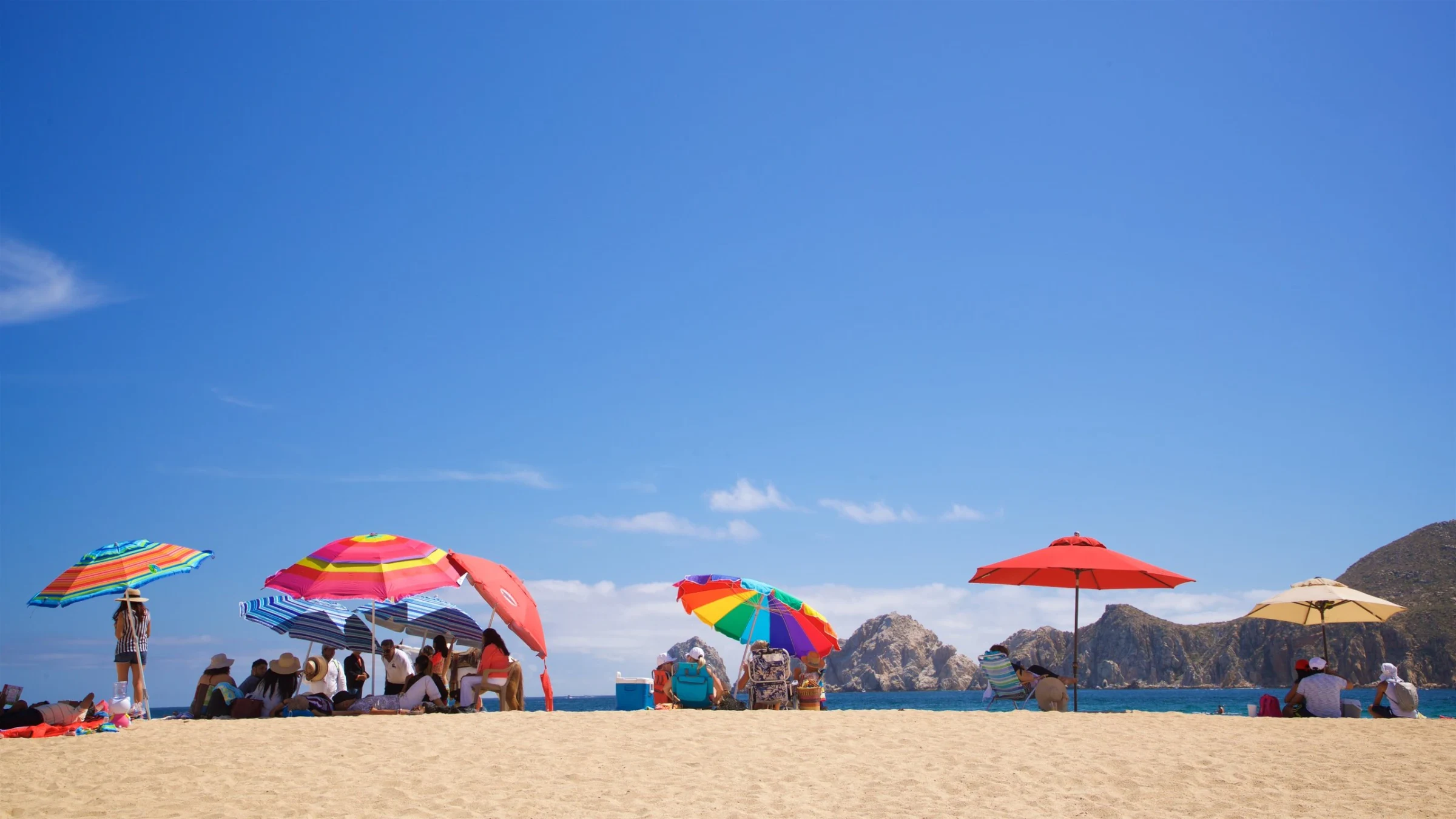 Colorful umbrellas on Medano Beach with the Arch in the distance
