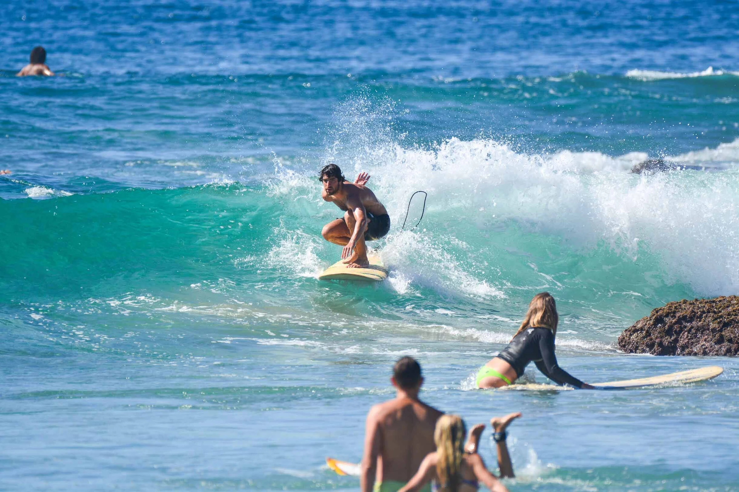 A beginner surfer riding a small teal wave at Cerritos