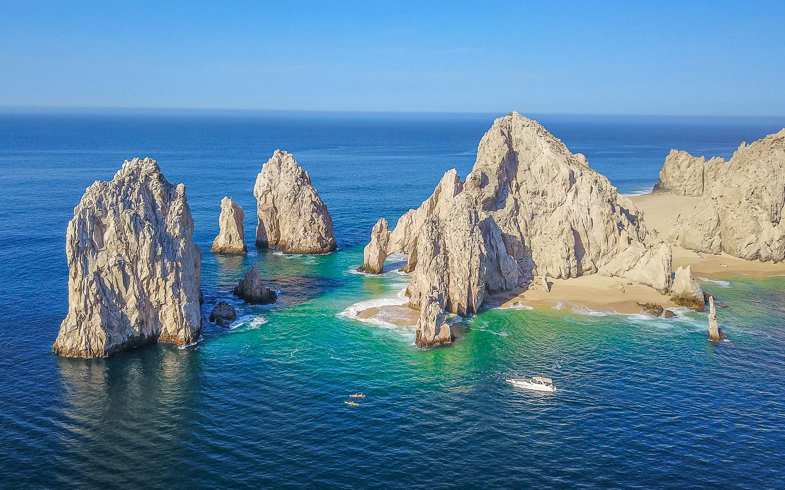 Aerial view of Lover's Beach and the granite rock formations of Land's End in Cabo San Lucas, with turquoise water and small boats in the bay
