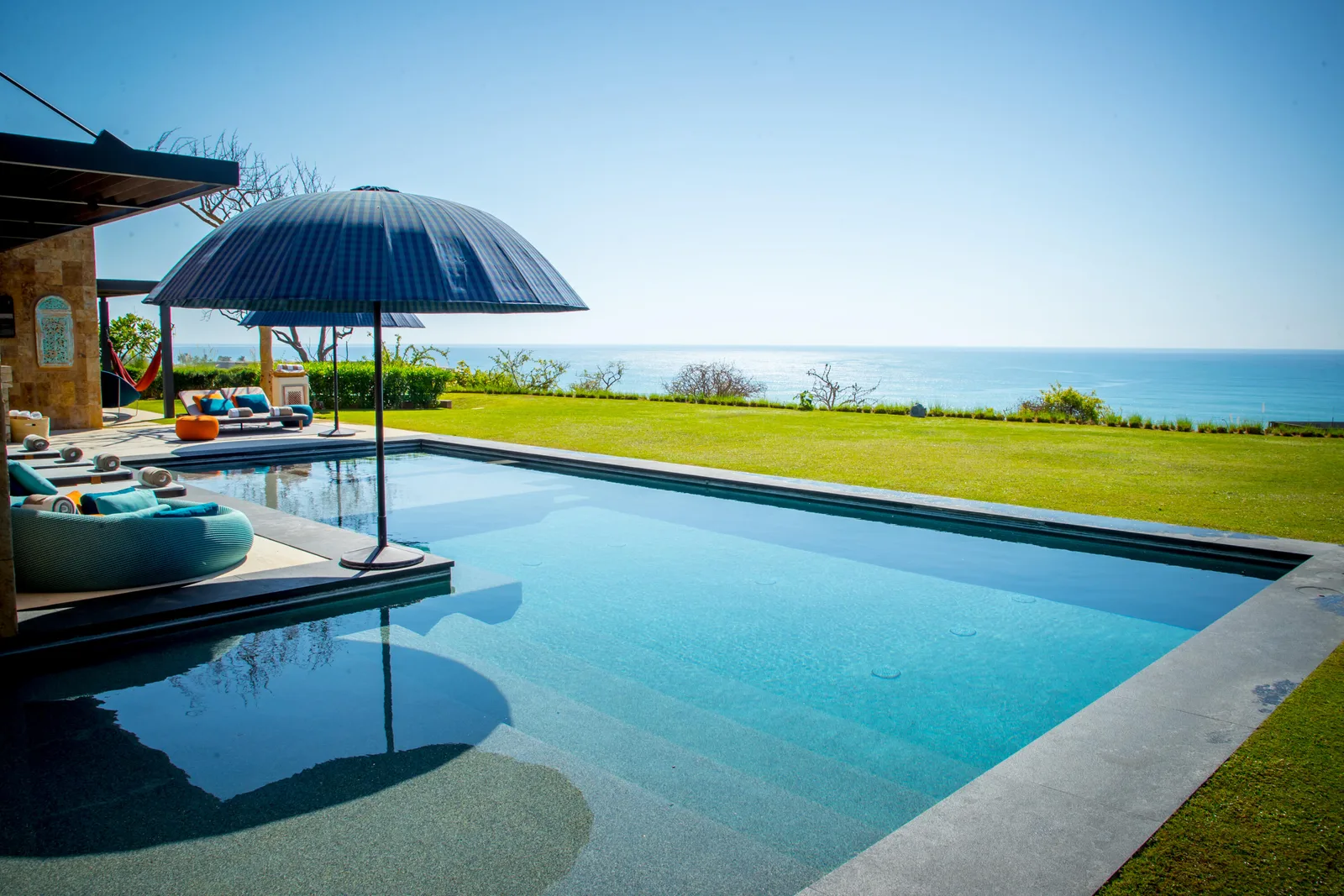 Infinity-edge pool on a green lawn overlooking the Sea of Cortez at a home in Puerto Los Cabos