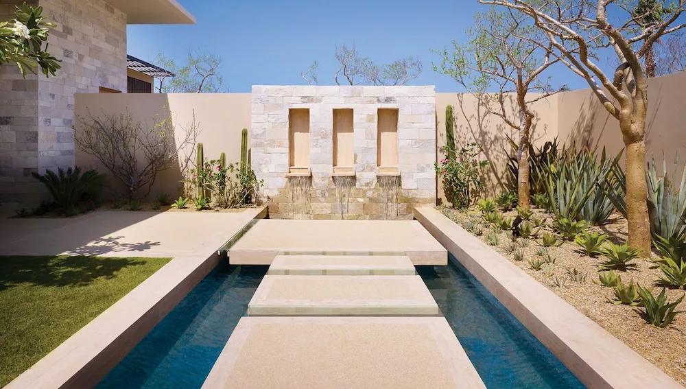 Stone stepping path over a long reflecting pool, framed by desert plants, at Montage Los Cabos
