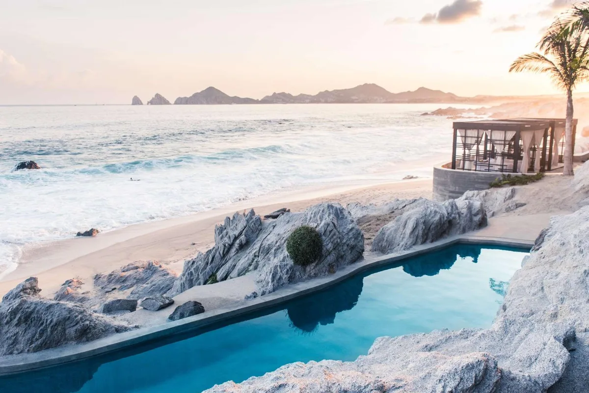 Pool carved into white rock above Monuments Beach at The Cape, with the Land's End rocks on the horizon