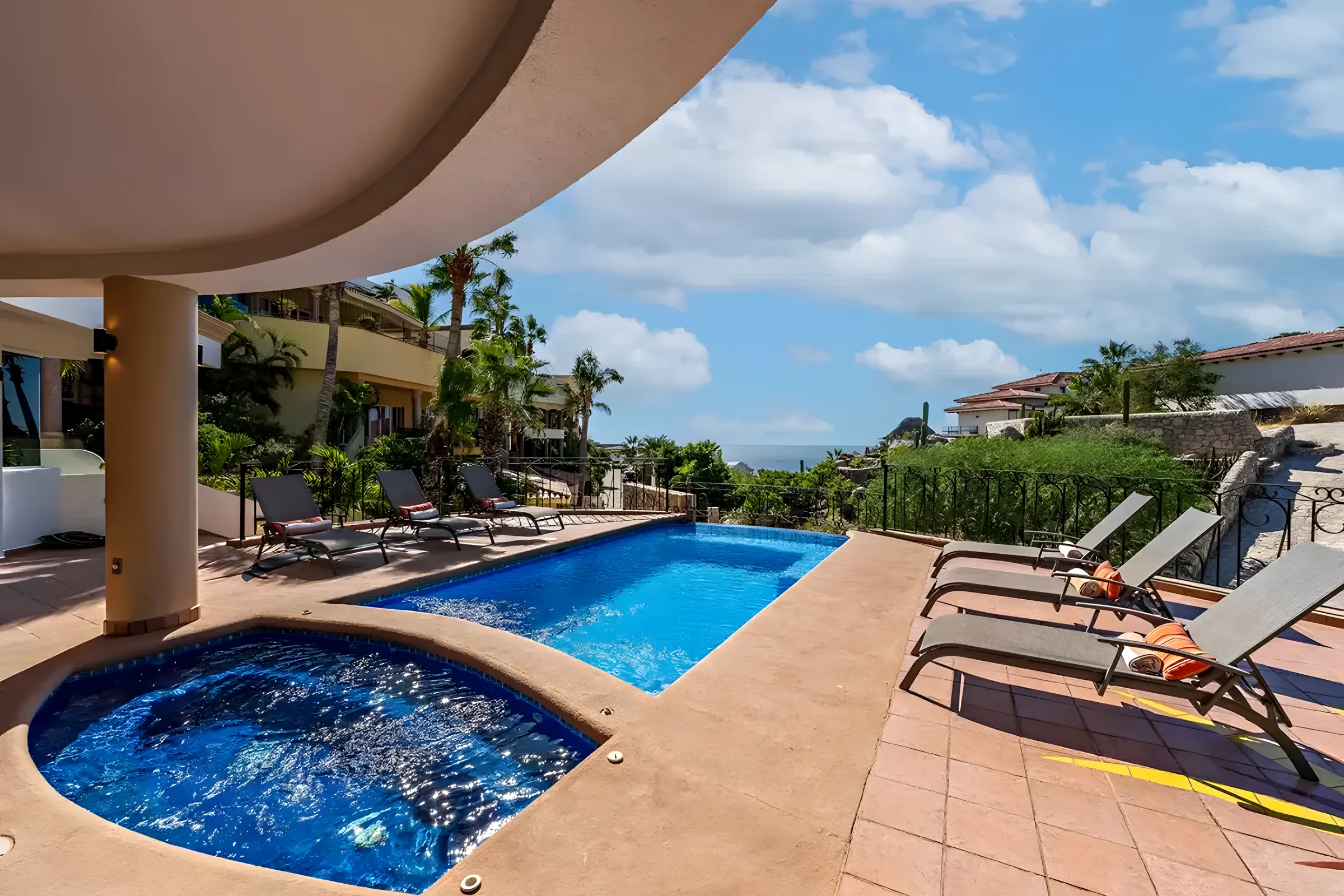 Villa Sol y Luna pool deck in Pedregal with a round jacuzzi in front of a rectangular pool, lounge chairs and a glimpse of the Pacific past the palms