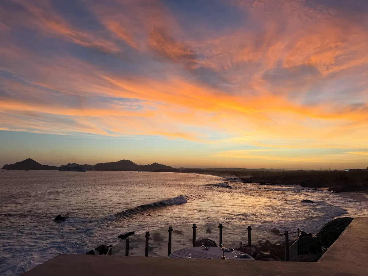 Orange and pink sunset sky over the rocky coastline below Sunset Monalisa in Cabo San Lucas